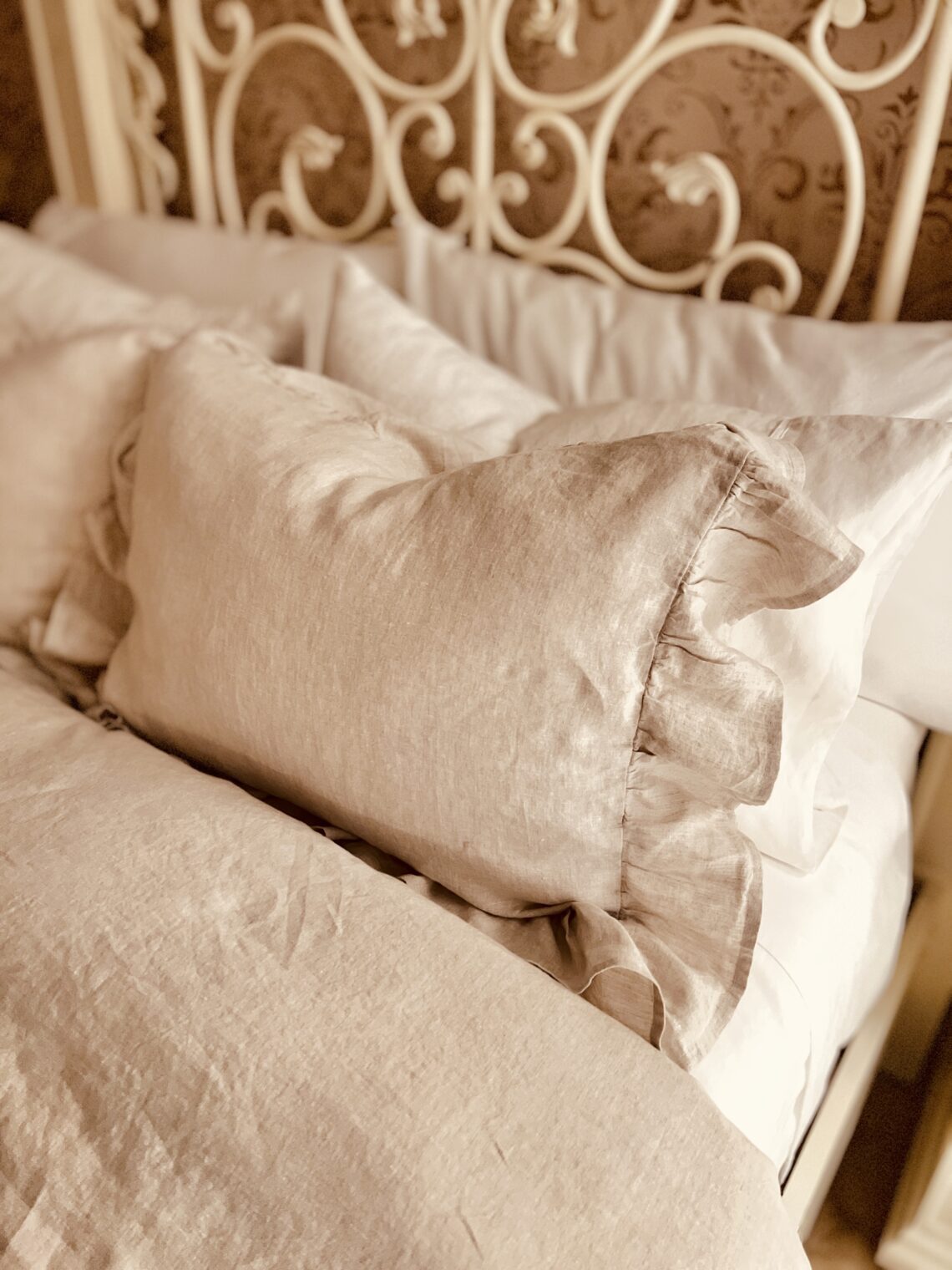 Linen bedding with ruffle edge natural neutral color French country bedroom makeover gel pillows Sleep Number bed wrought iron headboard painted white with chalk paint and all in one paint