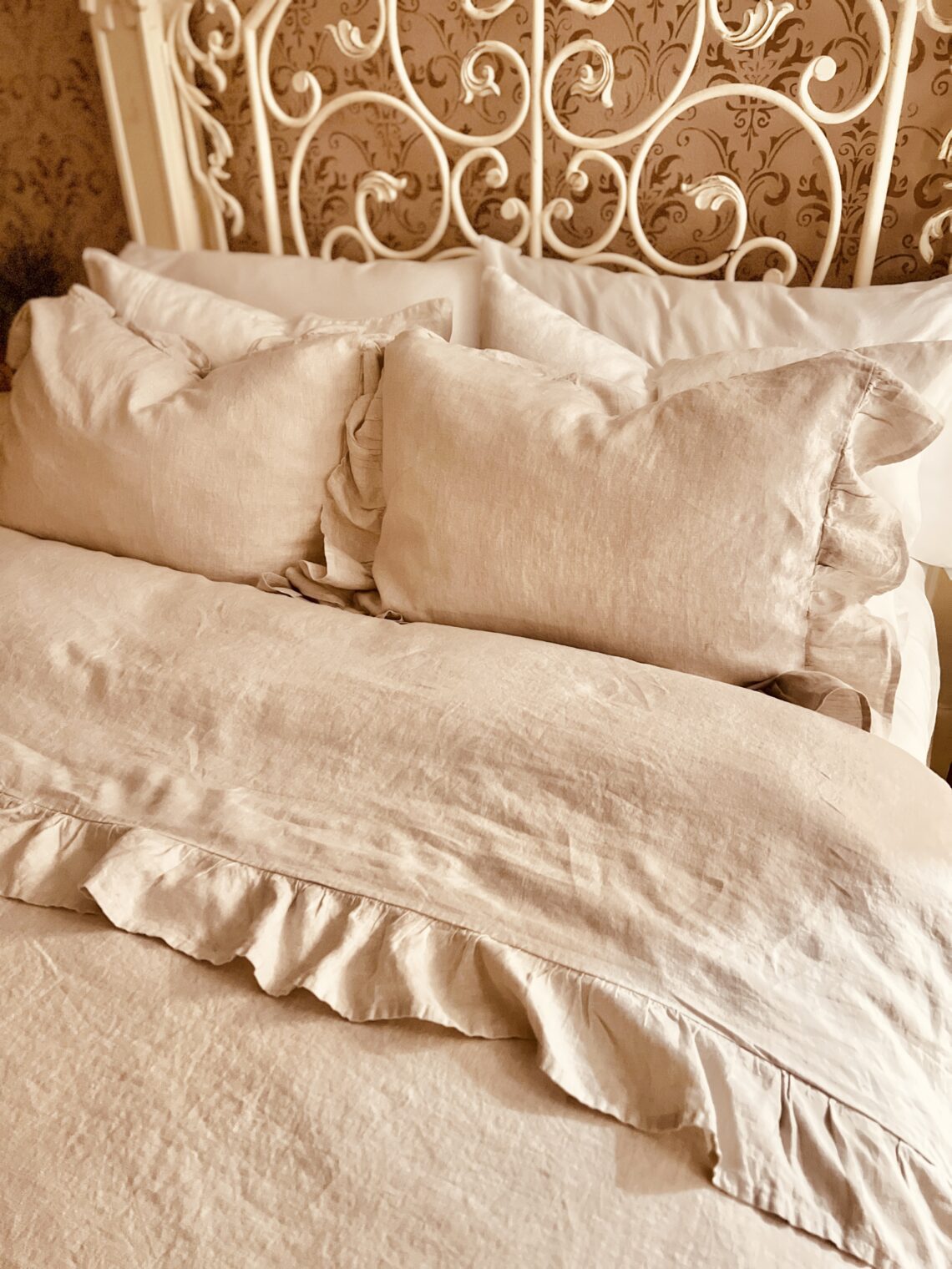 Linen bedding with ruffle edge natural neutral color French country bedroom makeover gel pillows Sleep Number bed wrought iron headboard painted white with chalk paint and all in one paint