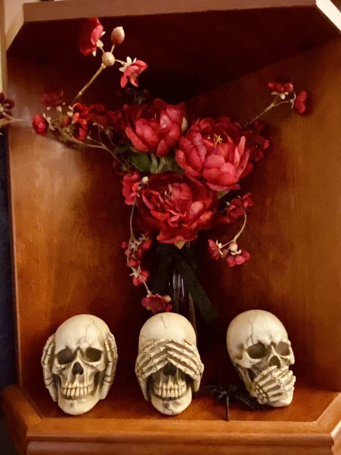 3 wise skulls see no evil hear no evil speak no evil on bookshelf with red flowers halloween decor