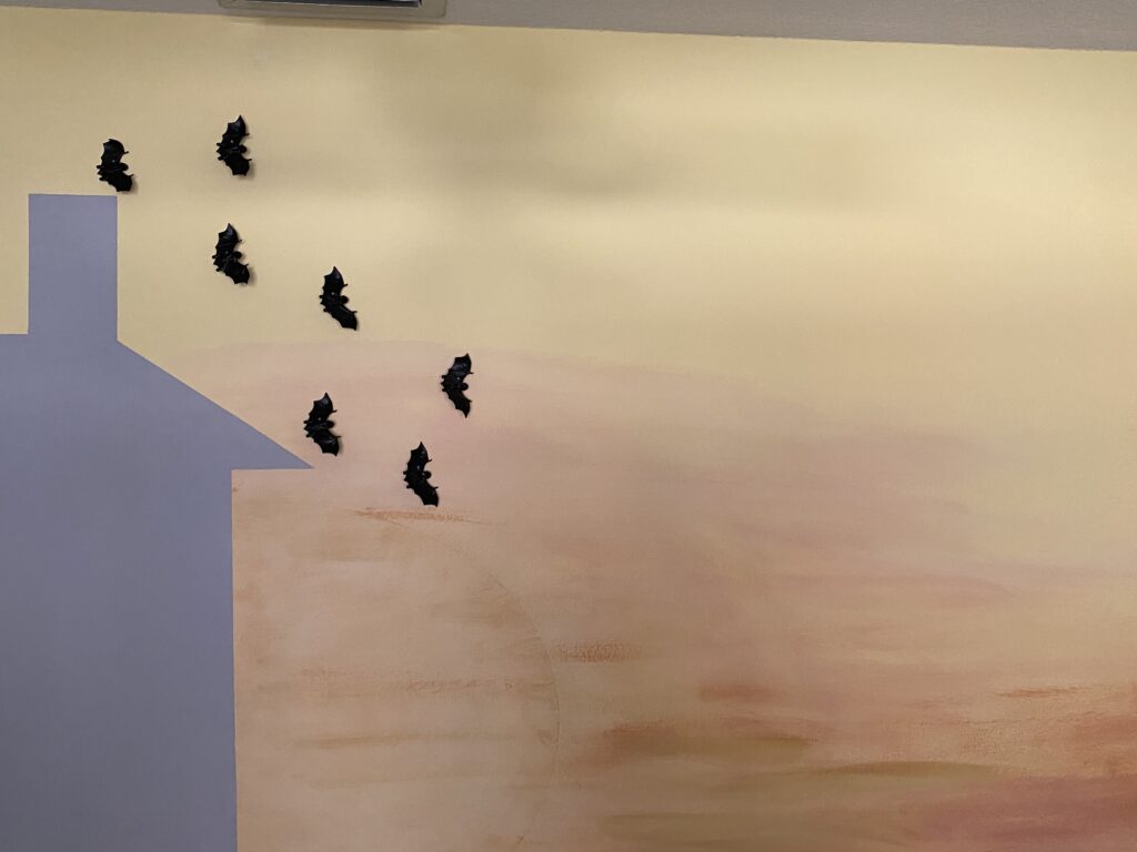 Halloween playroom decorations with bats flying over painted chimney on sunset wall